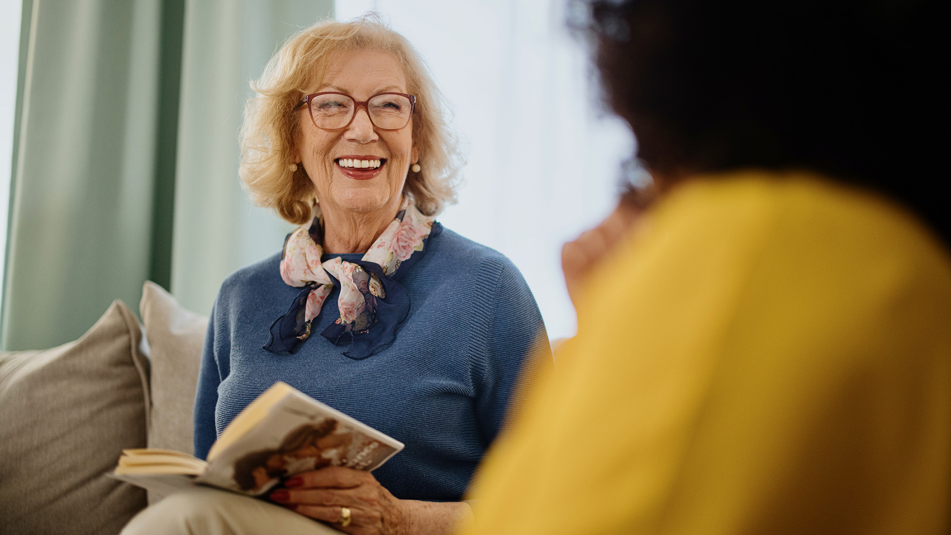 Group of people with a mixed age range talking and laughing while having a book club meeting